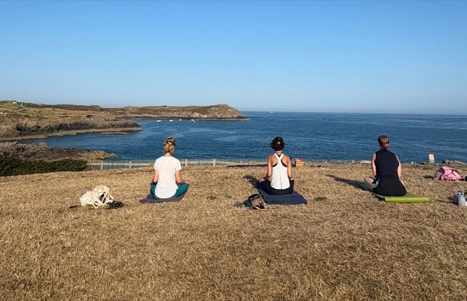 Trois pratiquants en méditation sur la pointe herbeuse, face à la mer à Saint-Malo