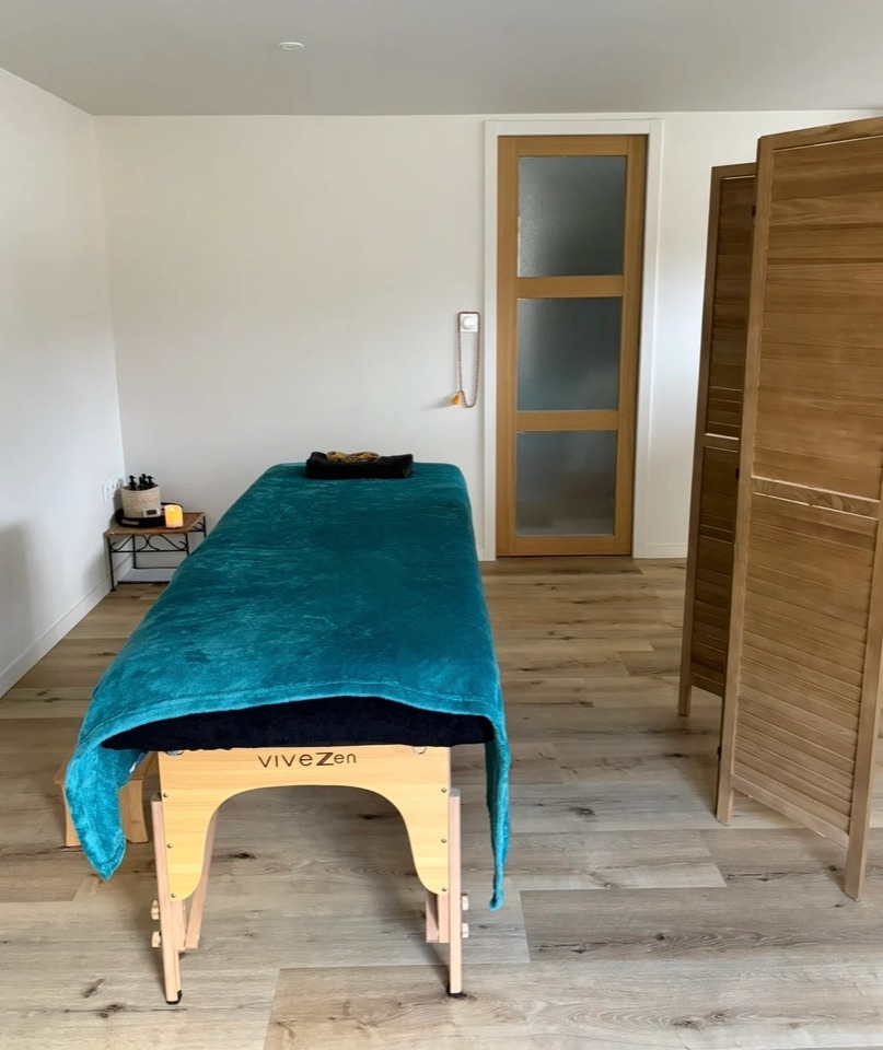 La table de massage et son paravent dans la salle de soin du studio